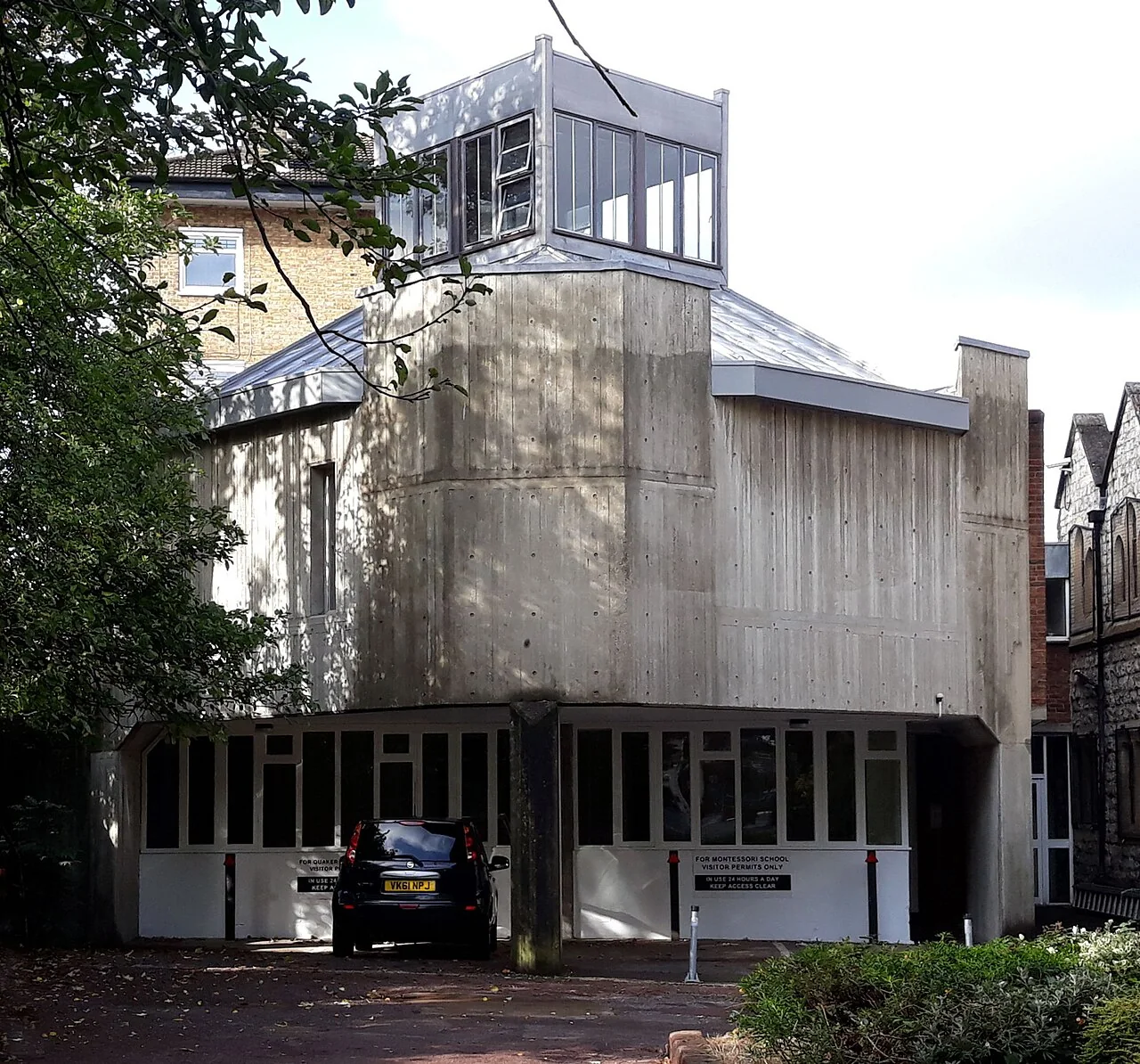 The Blackheath Quaker Meeting House, a board-marked concrete building with a glazed lantern on the roof and parking bays underneath