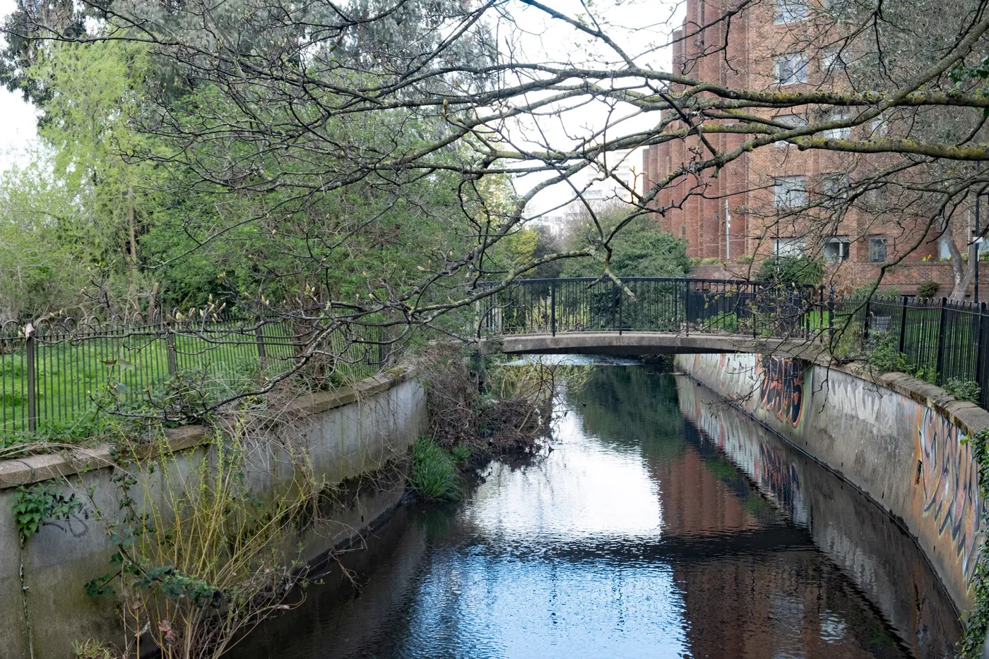 The River Ravensbourne runs through Lewisham town centre in a concrete channel, crossed by footbridges like this one, photographed in April 2023