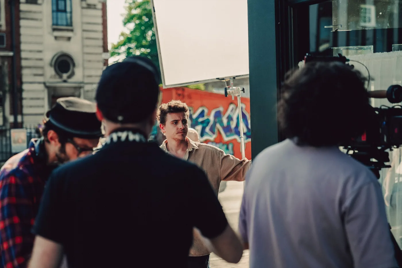 Crew members talking outside, with a colourful graffiti wall behind them