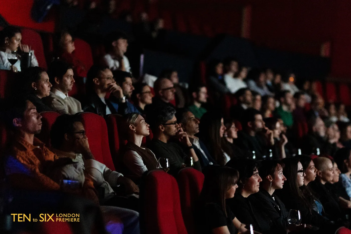Rows of audience members in red cinema seats watching the screen
