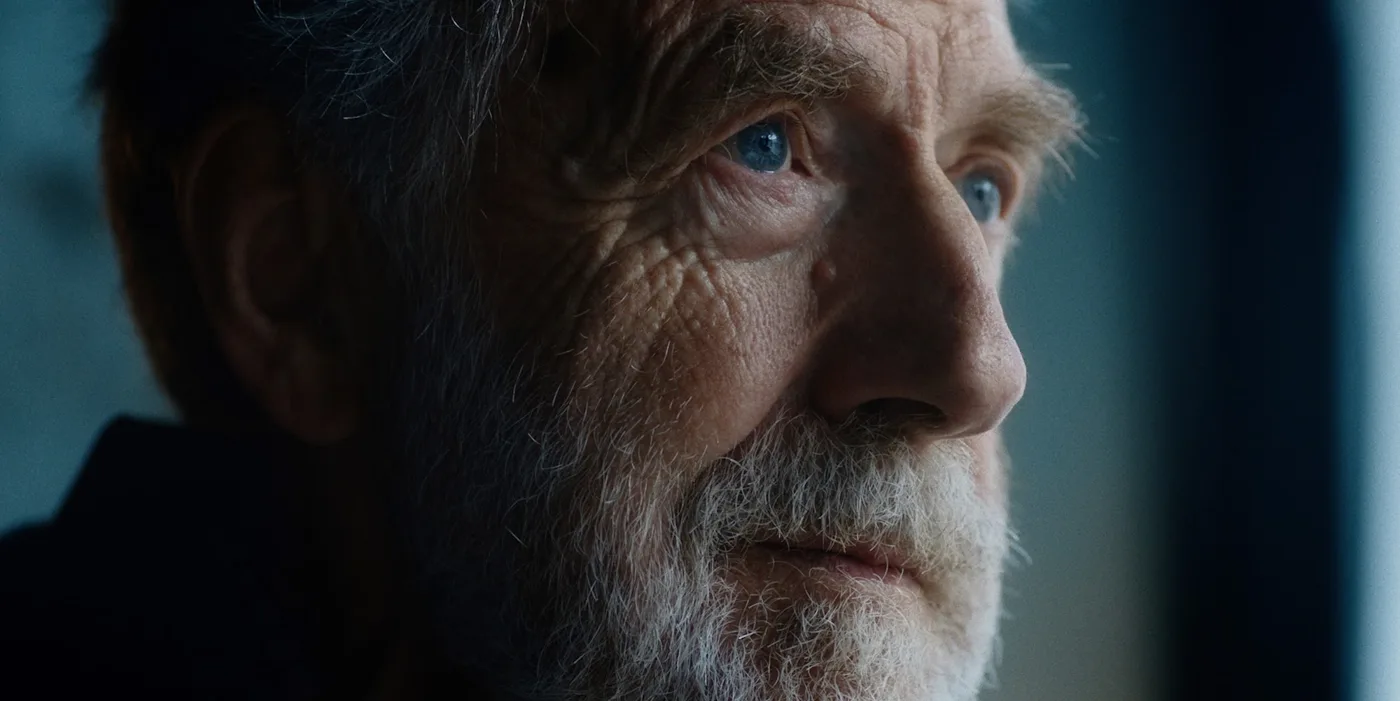 Close-up of an older man with a white beard looking out of a window, in a still from Ten to Six