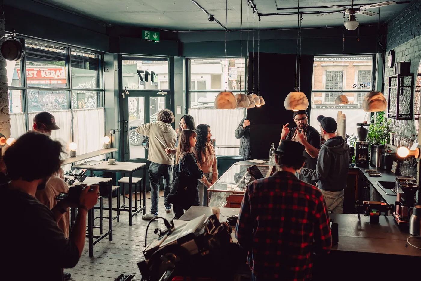 A film crew with cameras and equipment spread through a cafe interior